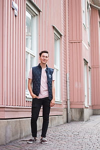 man wearing pink shirt and quilted black vest near pink painted wall thumbnail