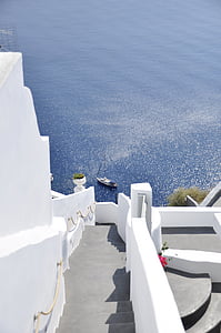 photo of staircase building near sea with boat during daytime thumbnail