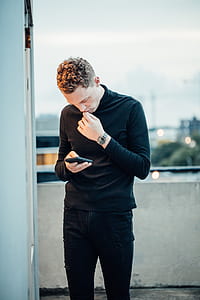 man standing while holding smartphone thumbnail