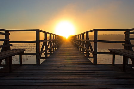 photo of brown wooden bench near ocean during sunrise thumbnail