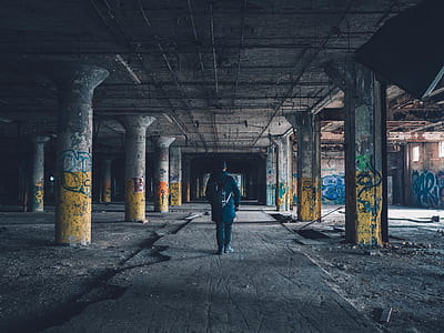 person walking between concrete post in building thumbnail