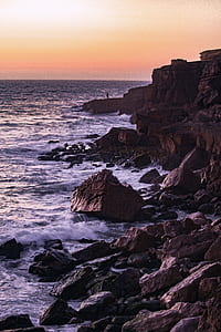man standing on cliff facing body of water thumbnail