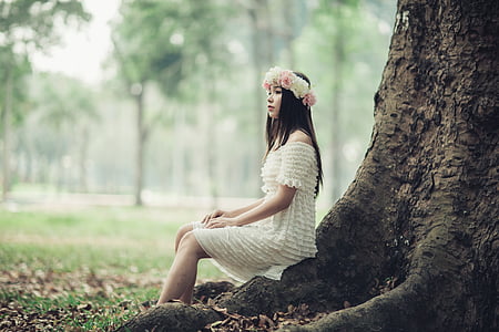 woman in white off-shoulder dress sitting near tree thumbnail