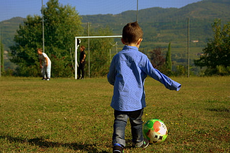 boy wearing blue dress shirt in front of multicolored ball in soccer field thumbnail