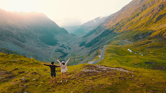man and woman standing on mountain while raising hands thumbnail