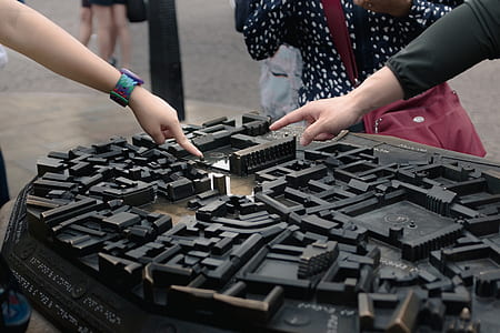 person pointing black miniature buildings thumbnail