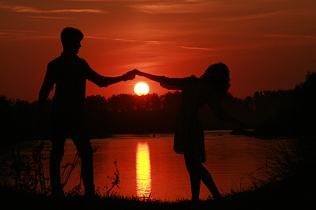 silhouette of man and woman dancing during sunset photo thumbnail
