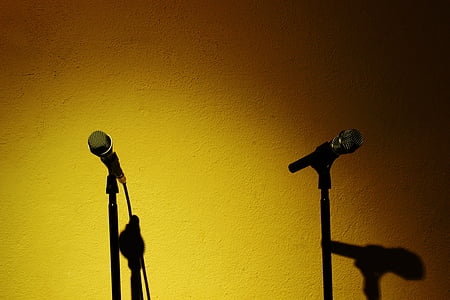 two black corded microphone with stands beside yellow painted wall thumbnail