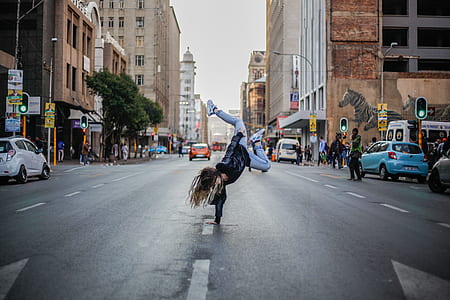 woman raising her body by hand on concrete road near building thumbnail