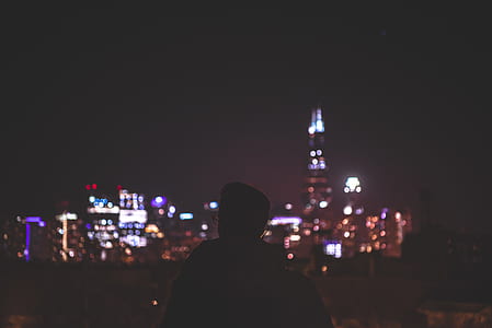 silhouette photo of person facing cityscape during night time thumbnail