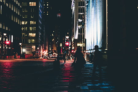 silhouette of man and woman walking beside high rise building during nighttime thumbnail
