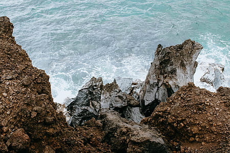 bird's eye photography of waves splashing through rock mountain thumbnail
