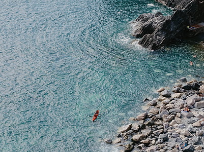 two people riding kayak near rock formation thumbnail