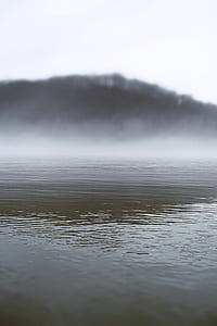 low-angle photography of body of water surrounded with fogs thumbnail