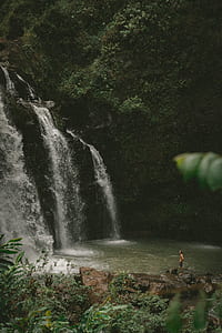 man standing in front of falls rushing in to the water thumbnail