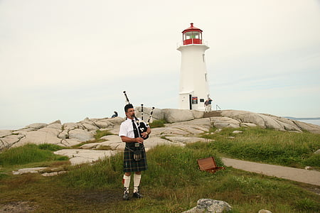 man playing bagpipe near lighthouse during daytime thumbnail