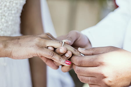 person putting wedding ring on ring finger of woman thumbnail