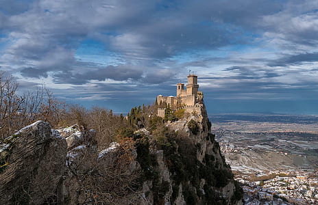 aerial view of brown concrete castle on mountain cliff thumbnail