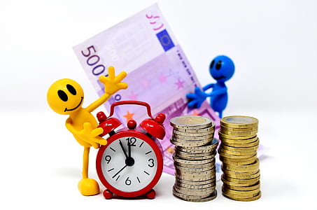 pile of coins beside red and white analog table clock and 5000 banknote thumbnail