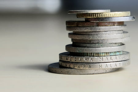 selective focus photography of stack of coins on white table thumbnail
