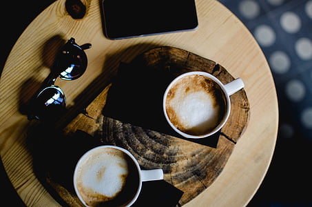 two lattes placed on brown wooden coaster thumbnail