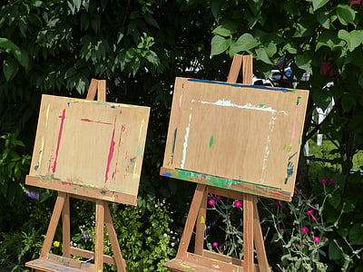 two brown wooden easel in front of green leafed plants thumbnail