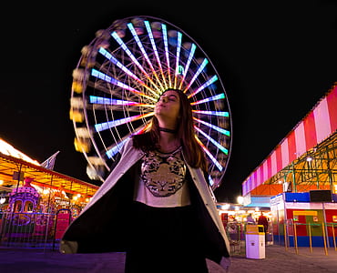woman standing front of Ferris wheel at night time thumbnail