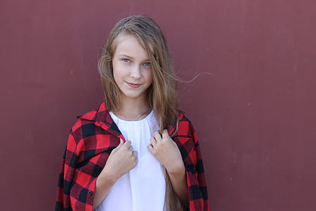 woman in white crew-neck blouse leaning on brown wall thumbnail