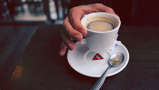 person holding cup of coffee by the table thumbnail
