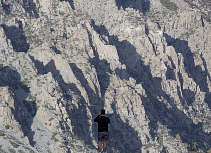 selective focus photography on man standing in front on mountain range during daytime thumbnail