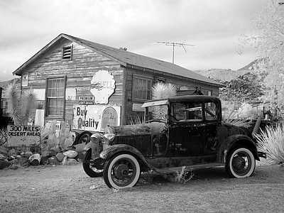 grayscale photography of vintage car near building thumbnail