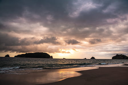 brown seashore during cloudy sky thumbnail