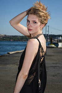 woman wearing black blouse standing near body of water thumbnail