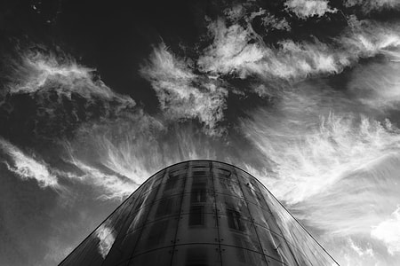 grayscale photography of building under cloudy sky thumbnail
