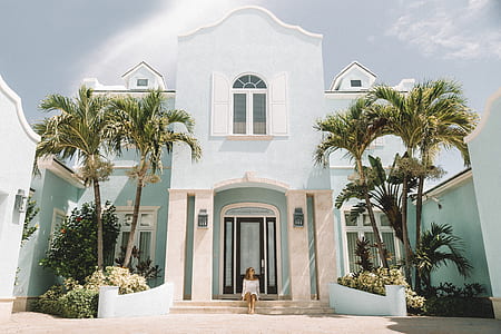 woman sitting in front of white two-storey house thumbnail