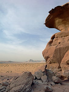 brown rock formation in desert under blue and white cloudy sky thumbnail