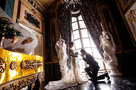 groom kneeling in front of his bride by the window thumbnail