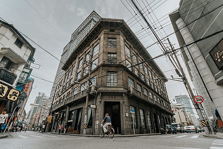 worm's eye view of person riding bicycle in front of gray building thumbnail