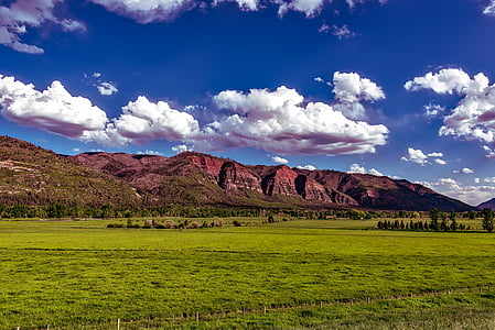 green grass field near brown mountain during daytime thumbnail