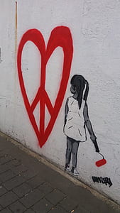 girl holding paint roller looking at heart mural on wall thumbnail