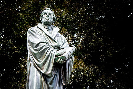 man holding book statue at daytime thumbnail