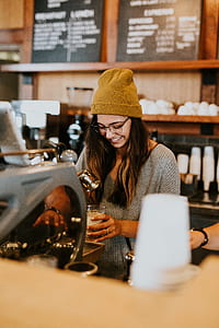 woman wearing gray v-neck top and brown bonnet holding clear glass thumbnail