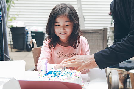 girl in front of birthday cake on table thumbnail
