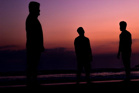 silhouette of three men standing on seashore thumbnail