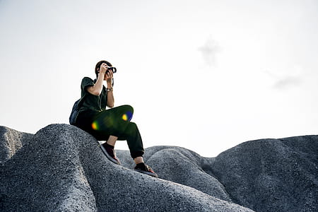 woman holding camera sitting on rock thumbnail