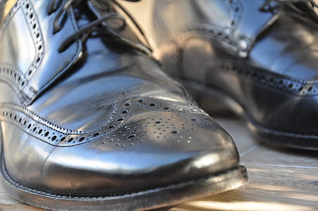 person wearing pair of black Oxford wingtip shoes thumbnail