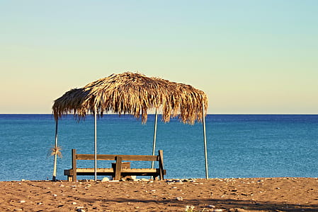 black wooden bench near beach thumbnail