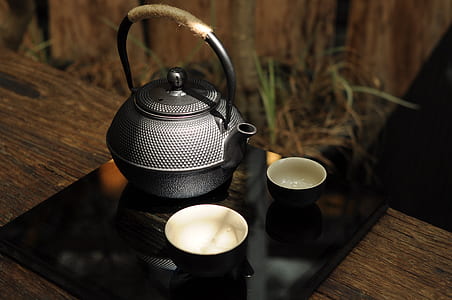 two round black bowls beside teapot on tray thumbnail