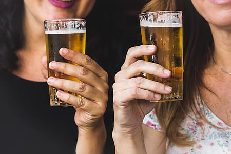 shallow focus photography of two woman holding beer glasses thumbnail