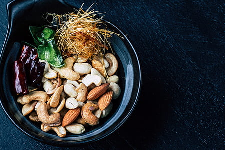 closeup photo of variety of nuts on black ceramic bowl thumbnail